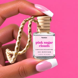 May include: A small clear glass oil diffuser bottle with a light wood cap and a gold-flecked beige hanging cord. The label reads femme luxe, pink sugar clouds, raspberry, cotton candy, caramel, vanilla, OIL DIFFUSER, and 0.33 fl. oz (10 ml).