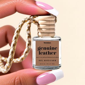 May include: A small clear glass oil diffuser bottle with a light brown wooden cap and a braided cord. The label is brown with black text reading femme luxe, genuine leather, amber, cedar, patchouli, labdanum, birch, saffron, OIL DIFFUSER, 0.33 FL. OZ (10 ML).