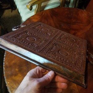 Pode incluir: Uma bandeja de cobre com um design em relevo ornamentado. A bandeja tem duas al&ccedil;as e uma borda elevada.