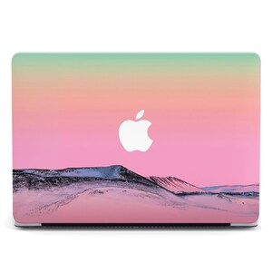 May include: A pink, green and yellow laptop skin with a white Apple logo and a snowy mountain landscape.