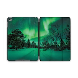 May include: A green and black iPad case with a design of a snowy forest and the aurora borealis in the sky.