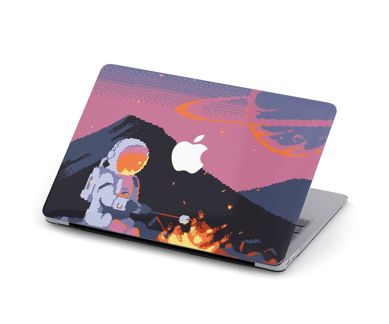 May include: A laptop with a pixelated design featuring an astronaut roasting marshmallows over a campfire in a pink and blue landscape. The laptop has an Apple logo on the lid.