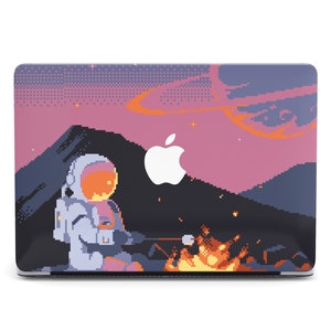 May include: A laptop skin with a pixelated design featuring an astronaut in a white spacesuit sitting by a campfire in a pink and purple sky with a galaxy background.