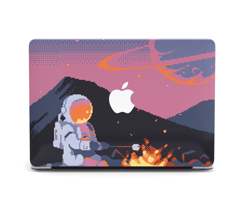 May include: A laptop skin with a pixelated design featuring an astronaut in a white spacesuit sitting by a campfire in a pink and purple sky with a galaxy background.