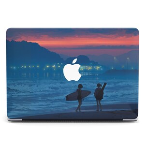 May include: A laptop computer with a sunset scene on the beach. The scene features two people silhouetted against the water, one holding a surfboard. The Apple logo is visible on the laptop screen.
