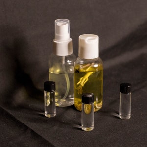 May include: Four glass bottles with different colored liquids. Two bottles have white spray tops, one bottle has a black cap, and one bottle has a black cap with a clear top.