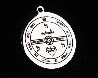 May include: A circular silver-toned metal pendant featuring an engraved design with a central hexagram, various symbols, and Hebrew-style lettering arranged in a circular border. The pendant includes a small loop at the top for attachment.