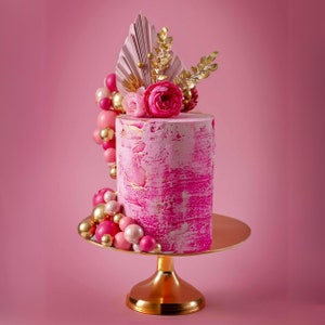 Torta finta fucsia: strati strutturati, dettagli dorati, decorazione floreale