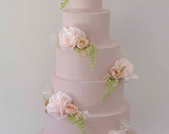 May include: A five-tiered pink wedding cake decorated with delicate pink and white flowers and greenery.