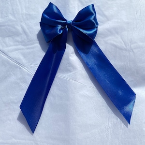 May include: A large blue satin bow with long tails. The bow is tied in a classic style with the tails extending out to the sides.