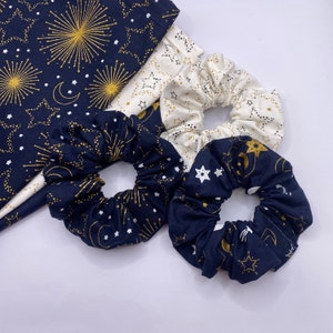 Puede incluir: Tres scrunchies para el pelo con un patr&oacute;n de estrellas y medias lunas azul marino y blanco. Los scrunchies est&aacute;n hechos de tela suave y son perfectos para a&ntilde;adir un toque de estilo a cualquier atuendo.