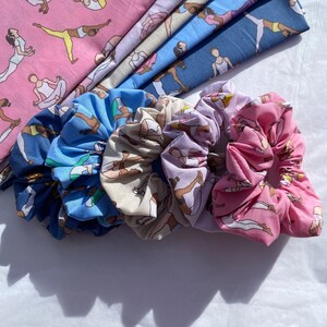 May include: Four colourful hair scrunchies featuring a pattern of women performing yoga poses. The scrunchies are made from soft fabric and are ideal for keeping your hair in place.