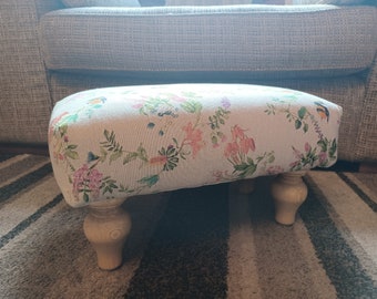 Hand crafted footstool in a bee and flower material with neutral background and tulip style feet