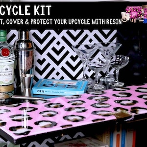 May include: A pink and black leopard print tray with a clear resin coating. The tray is sitting on top of a black and white chevron patterned surface. The text "UPCYCLE KIT" is written in white letters on a black background. The text "PAINT, COVER & PROTECT YOUR UPCYCLE WITH RESIN" is written in white letters on a black background.