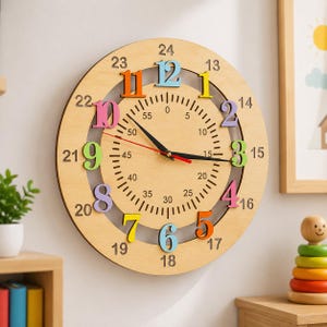 May include: A round wooden wall clock featuring a dual-layer design with colorful raised numbers. The outer ring displays numbers 13 through 24, while the inner circle shows 1 through 12. A central dial includes minute markers from 0 to 55.
