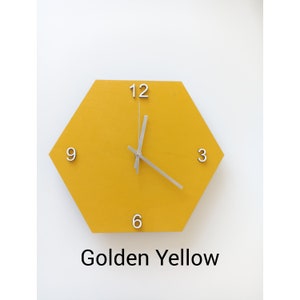 May include: A hexagonal clock with a golden yellow face and silver hands. The numbers 12, 9, 3, and 6 are printed on the face. The text "Golden Yellow" is printed below the clock.