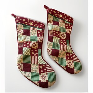 May include: Two Christmas stockings featuring a patchwork design of burgundy, forest green, and cream squares. The fabric displays alternating patterns of stripes, star motifs, and geometric shapes. Each stocking has a small fabric loop at the top.