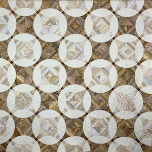 May include: A handmade quilt with a repeating pattern of circles and squares. The quilt features a neutral color palette of beige, cream, and brown. The design is intricate, with detailed stitching and patchwork.
