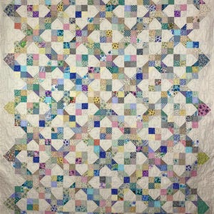 May include: A large quilt with a patchwork design featuring a variety of floral and geometric patterns in shades of pink, blue, green, yellow, and white. The quilt is quilted with a heart-shaped design.
