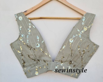 May include: A light gray sleeveless blouse with a deep V-neckline. The blouse is decorated with silver and gold sequins in a floral pattern. The text "sewinstyle" is visible in the bottom center of the image.