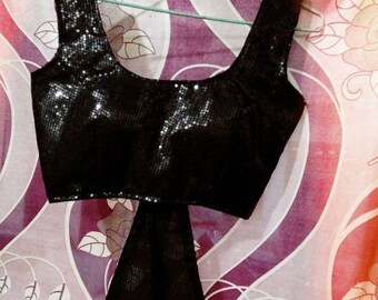 May include: A black sequined crop top with a tie at the back. The top is sleeveless and has a scoop neckline.