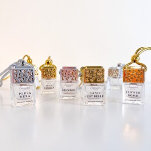 May include: Five small glass bottles with gold lids and decorative designs. Each bottle has a different scent: Spicy Vanilla, Sauvage, La Vie Est Belle, Flower Bomb, and Perla Nera. The bottles are labeled with the scent name and "Salvati's Candle Diffusore per Auto".