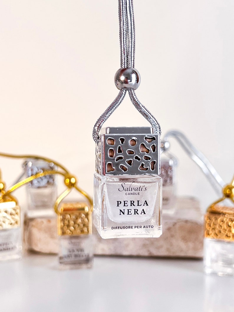 May include: A silver car air freshener with a decorative metal cage and a clear glass bottle. The bottle contains a fragrance called "Perla Nera" by Salvati's Candle. The text on the bottle reads "Diffusore per Auto".