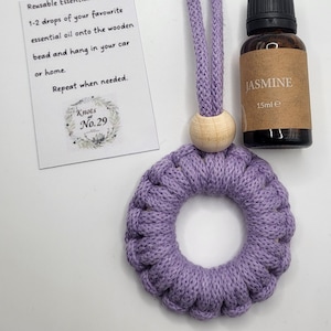 May include: Purple crocheted ring diffuser with a wooden bead and a string for hanging. A small bottle of jasmine essential oil is included. The card reads "Reusable Essential Oil Diffuser 1-2 drops of your favourite essential oil onto the wooden bead and hang in your car or home. Repeat when needed. Knots No.29"