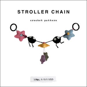 Peut inclure: Chaîne de poussette faite à la main avec des éléments crochetés. Elle comprend des personnages noirs avec des yeux blancs, des étoiles roses et bleues, et une pièce centrale jaune. Le texte "Stroller Chain" et "crochet pattern" est affiché.