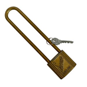 May include: A vintage brass padlock with a long shackle and a key. The lock has a rectangular body with the word "Slaymaker" and "Rustless" printed on it. The key is attached to a small metal ring.