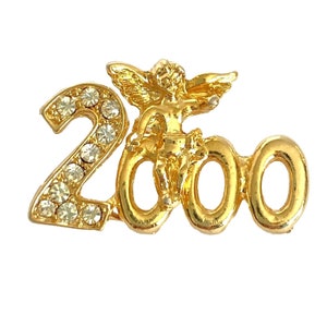 Op de afbeelding: Gouden 2000-jaarspeld met een cherubijnfiguur in het midden en strasssteentjes op het cijfer 2.