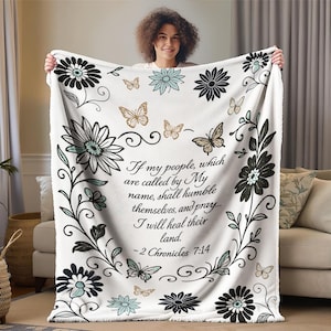 May include: White fleece blanket with a floral and butterfly design. The blanket features black and teal flowers, gold butterflies, and the text "If my people... I will heal their land. -2 Chronicles 7:14."