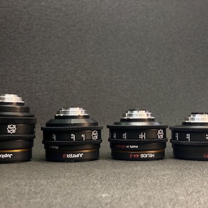 May include: Four black camera lenses with gold accents and white text. The lenses are labelled "Jupiter 37", "Jupiter 8", "Helios 44-2", and "Mir-1V".