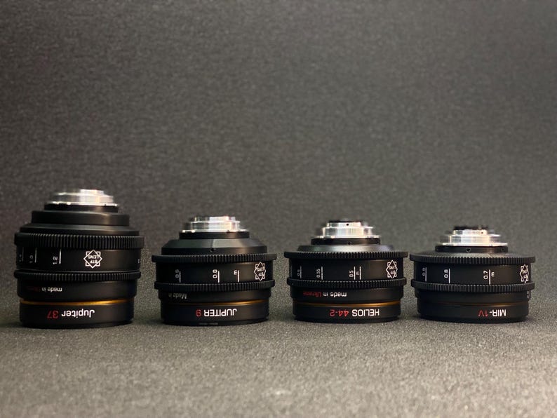 May include: Four black camera lenses with gold accents and white text. The lenses are labelled "Jupiter 37", "Jupiter 8", "Helios 44-2", and "Mir-1V".
