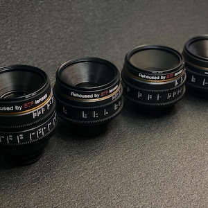 May include: Four black camera lenses with silver and gold accents. Each lens has the text "Rehoused by BTF lenses" printed on the side.