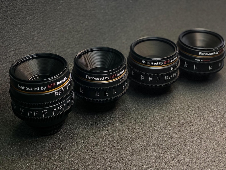 May include: Four black camera lenses with silver and gold accents. Each lens has the text "Rehoused by BTF lenses" printed on the side.