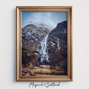 Può includere: Una fotografia incorniciata di una cascata che scende lungo un fianco roccioso in Scozia. La montagna è parzialmente ricoperta di neve e il cielo è nuvoloso. Il testo "Magical Scotland" è stampato sotto la cornice.
