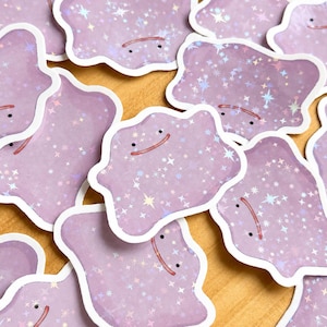 May include: A collection of die-cut stickers featuring a blob-shaped character in light purple with a holographic star pattern. Each sticker displays two small black dots for eyes and a simple curved line for a mouth, with a white border.