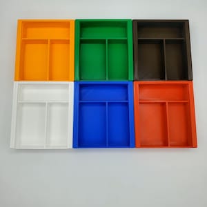 May include: Six small, rectangular storage trays with dividers. The trays are in six different colors: orange, green, brown, white, blue, and red.