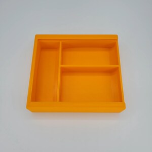 May include: Orange plastic tray with three compartments. The tray is empty.