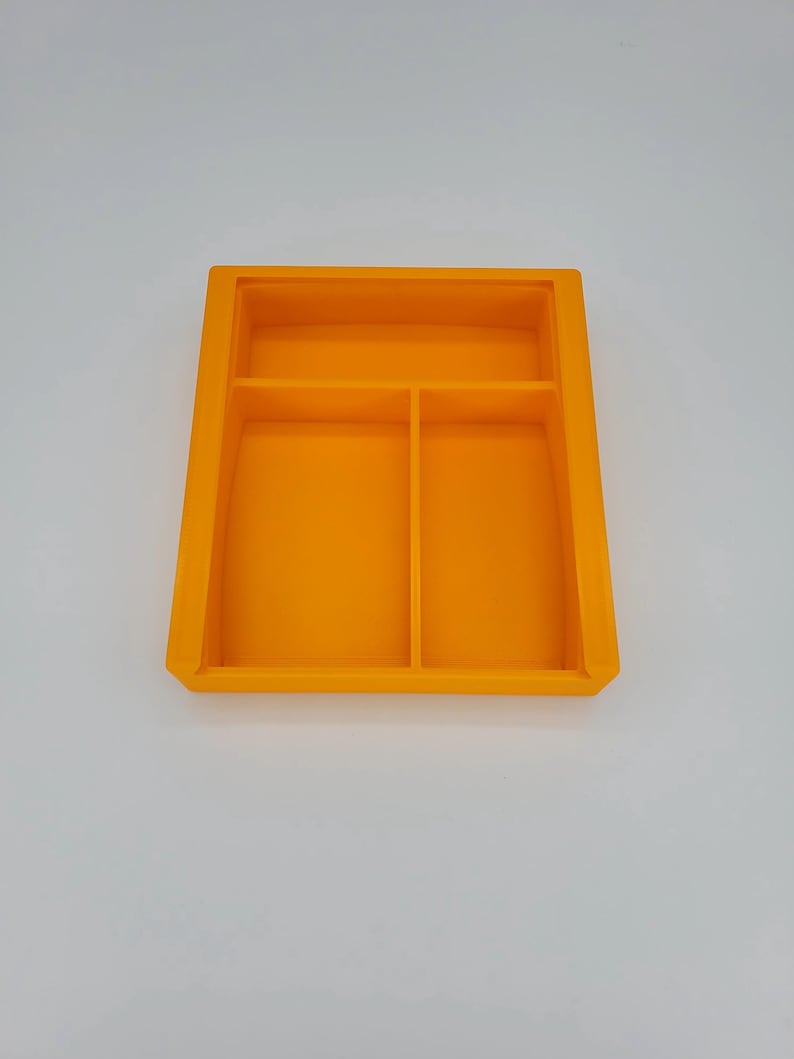 May include: Orange plastic tray with three compartments. The tray is divided into two smaller compartments and one larger compartment.