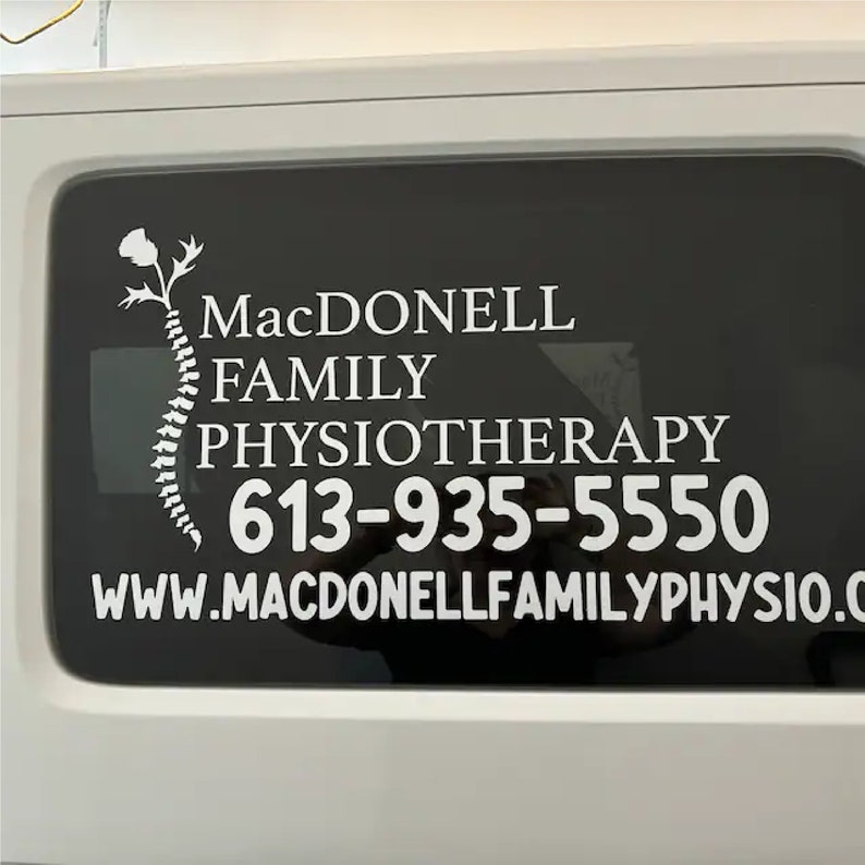 May include: White vinyl decal on a black background with the text "MacDonnell Family Physiotherapy" and the phone number "613-935-5550". The website address "www.macdonnellfamilyphysio.com" is also included.
