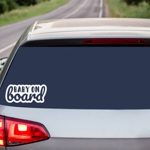 May include: A white car with a rear window sticker that says "BABY ON board" in a white cursive font.