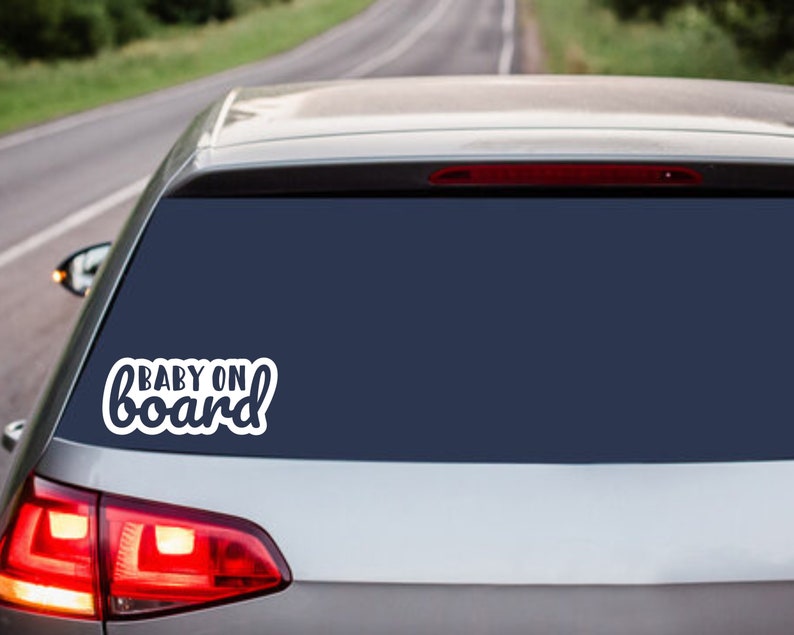 May include: A white car with a rear window sticker that says "BABY ON board" in a white cursive font.