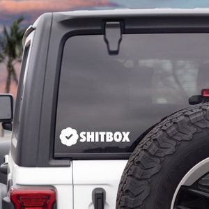 May include: White Jeep with a white checkmark and the text "SHITBOX" on the back window.