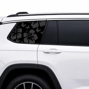 May include: A black hibiscus and butterfly decal applied to a car window. The floral design is visible against the dark tinted glass, creating a decorative accent. The decal is on the rear passenger window of a white SUV.