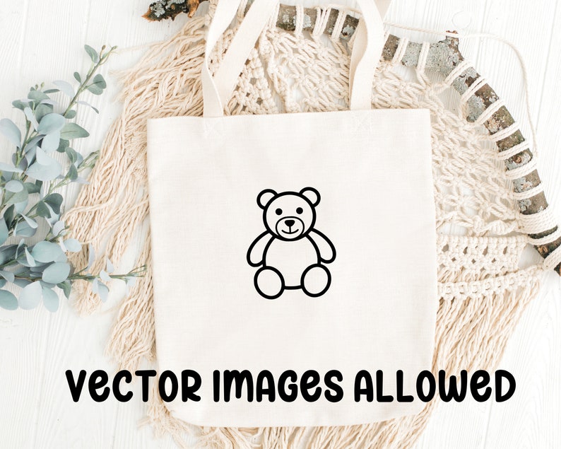 May include: Cream-colored tote bag with a black outline of a teddy bear. The words "vector images allowed" are printed in black at the bottom of the bag. The bag has two handles and is sitting on a white surface.