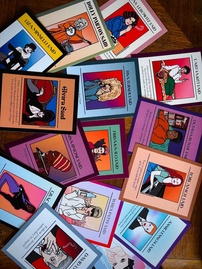 May include: A collection of colorful art prints featuring illustrations of famous women with quotes. The prints include portraits of Dolly Parton, Tina Turner, and Frida Kahlo, among others. Each print has a unique color scheme and design.