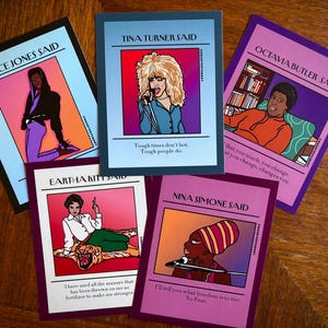 May include: A collection of five art cards featuring illustrations of famous women. Each card has a portrait and a quote attributed to the person. The cards have a colorful design with text that reads "Grace Jones Said", "Tina Turner Said", "Octavia Butler Said", "Eartha Kitt Said", and "Nina Simone Said".