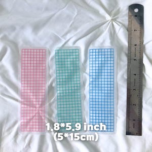 May include: Three grid-patterned bookmarks in pink, green, and blue, each measuring 1.8 x 5.9 inches. A metal ruler is placed next to the bookmarks. The text on the image reads "1.8*5.9 inch (5*15cm)".